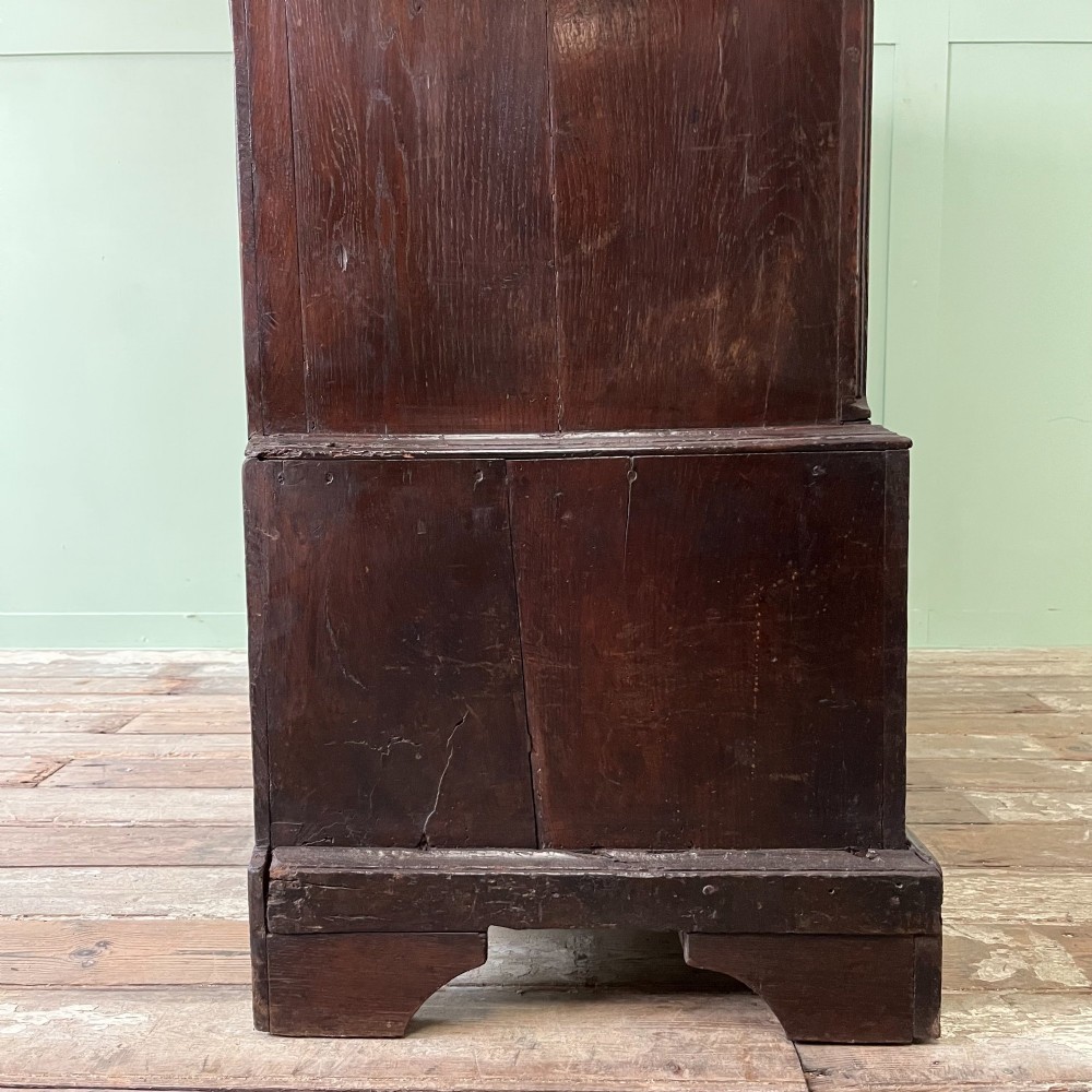 An 18th-century dark oak low linen press cupboard featuring arched fielded panel doors over a base with four drawers and brass handles. View XIII