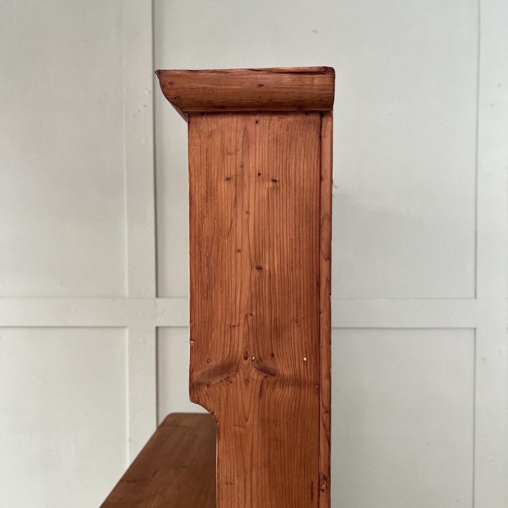 An early twentieth-century pine kitchen dresser featuring an open top display rack with two shelves above a two-door cabinet base with brass ring handles. View VII