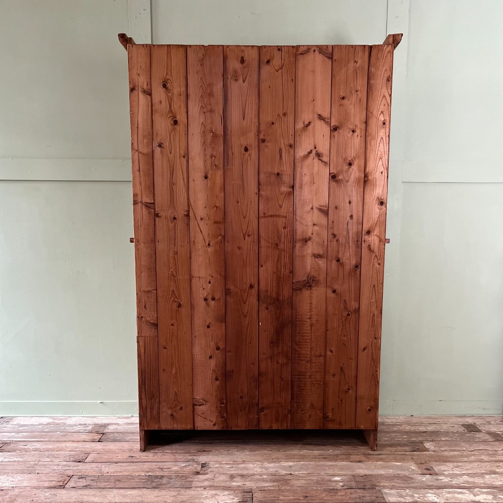 An early twentieth-century pine kitchen dresser featuring an open top display rack with two shelves above a two-door cabinet base with brass ring handles. View IX