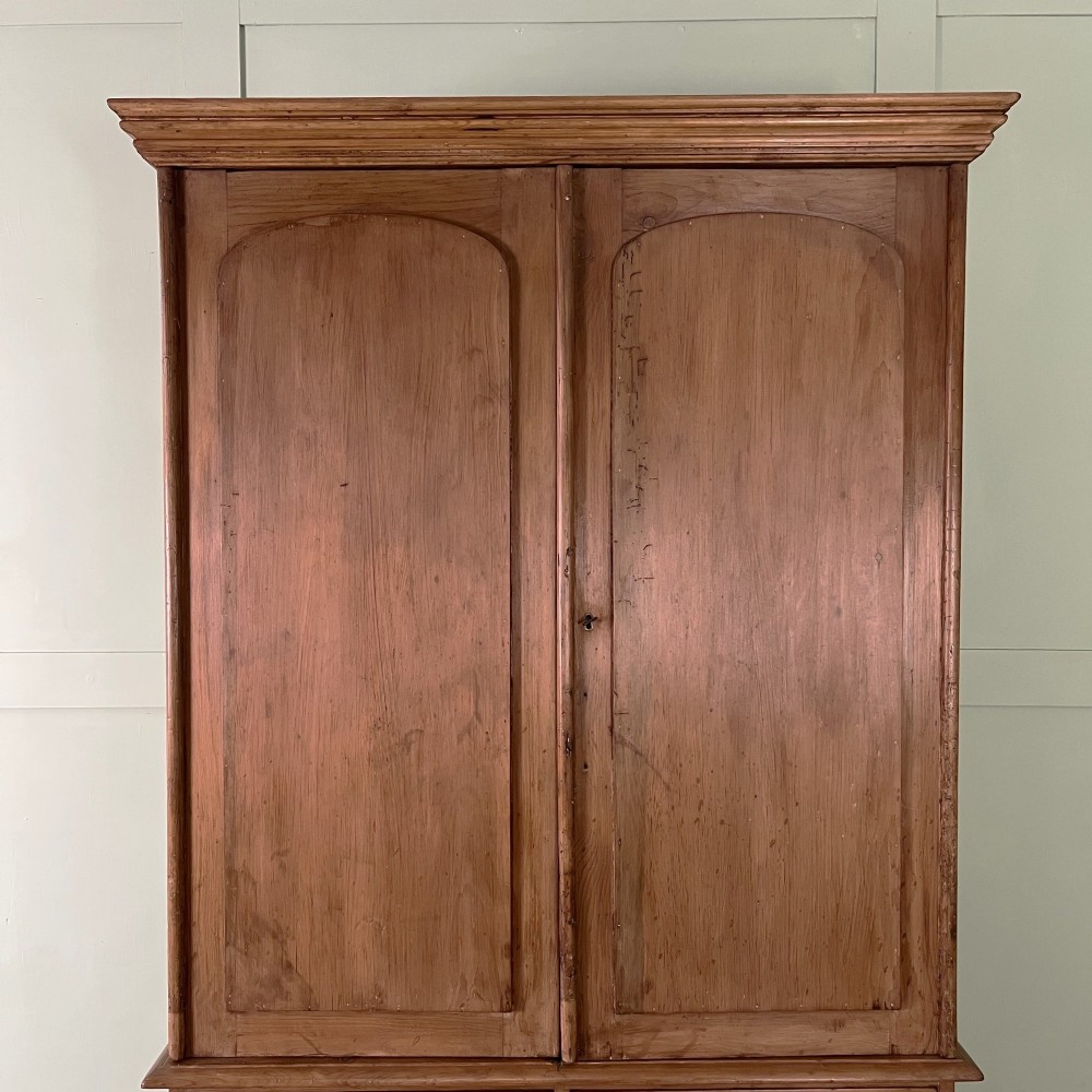 An antique Victorian pine cupboard on chest featuring a top section with two arched panel doors above three drawers with turned wooden handles. View II