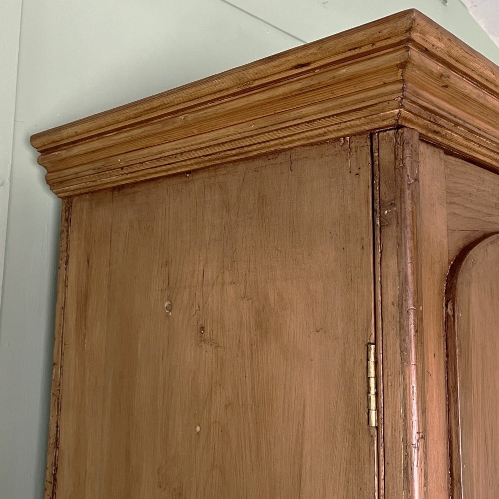 An antique Victorian pine cupboard on chest featuring a top section with two arched panel doors above three drawers with turned wooden handles. View VII