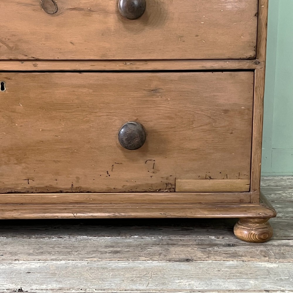 An antique Victorian pine cupboard on chest featuring a top section with two arched panel doors above three drawers with turned wooden handles. View IX