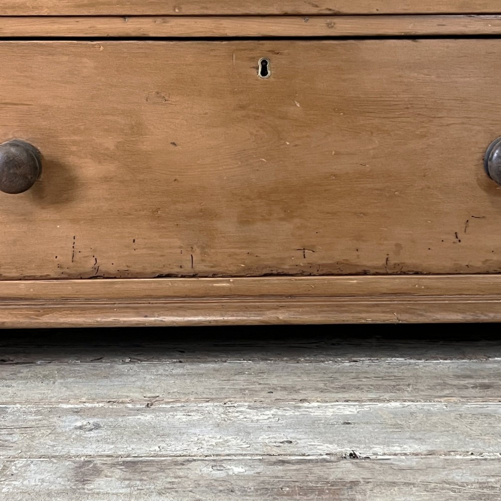 An antique Victorian pine cupboard on chest featuring a top section with two arched panel doors above three drawers with turned wooden handles. View XI