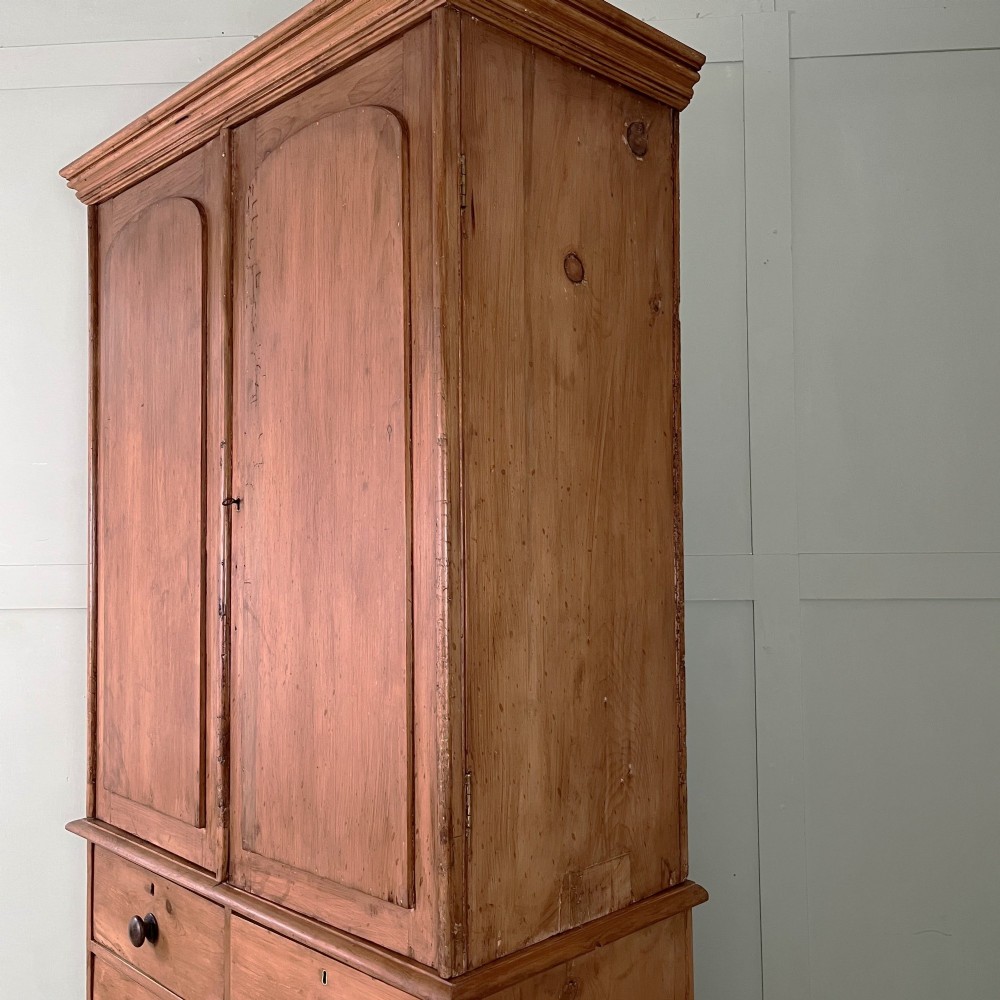 An antique Victorian pine cupboard on chest featuring a top section with two arched panel doors above three drawers with turned wooden handles. View XIII