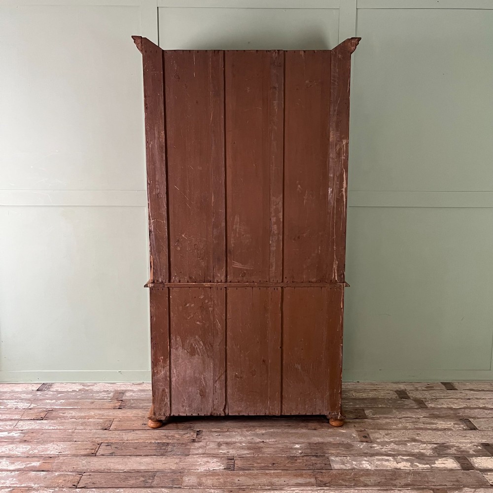 An antique Victorian pine cupboard on chest featuring a top section with two arched panel doors above three drawers with turned wooden handles. View XV
