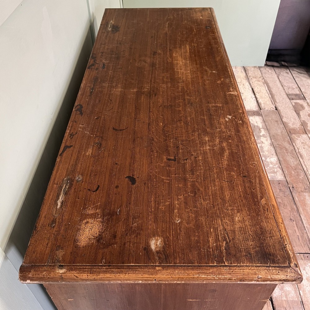 An antique Victorian warm brown pine cupboard featuring three drawers on the left with turned wooden knobs alongside a single panelled door on the right. View VII