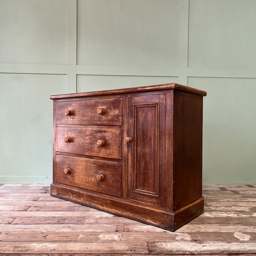 An antique Victorian warm brown pine cupboard featuring three drawers on the left with turned wooden knobs alongside a single panelled door on the right. View VIII