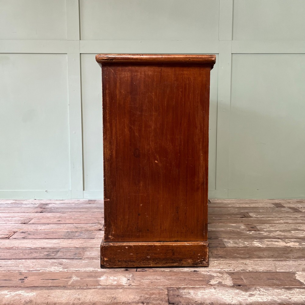 An antique Victorian warm brown pine cupboard featuring three drawers on the left with turned wooden knobs alongside a single panelled door on the right. View IX