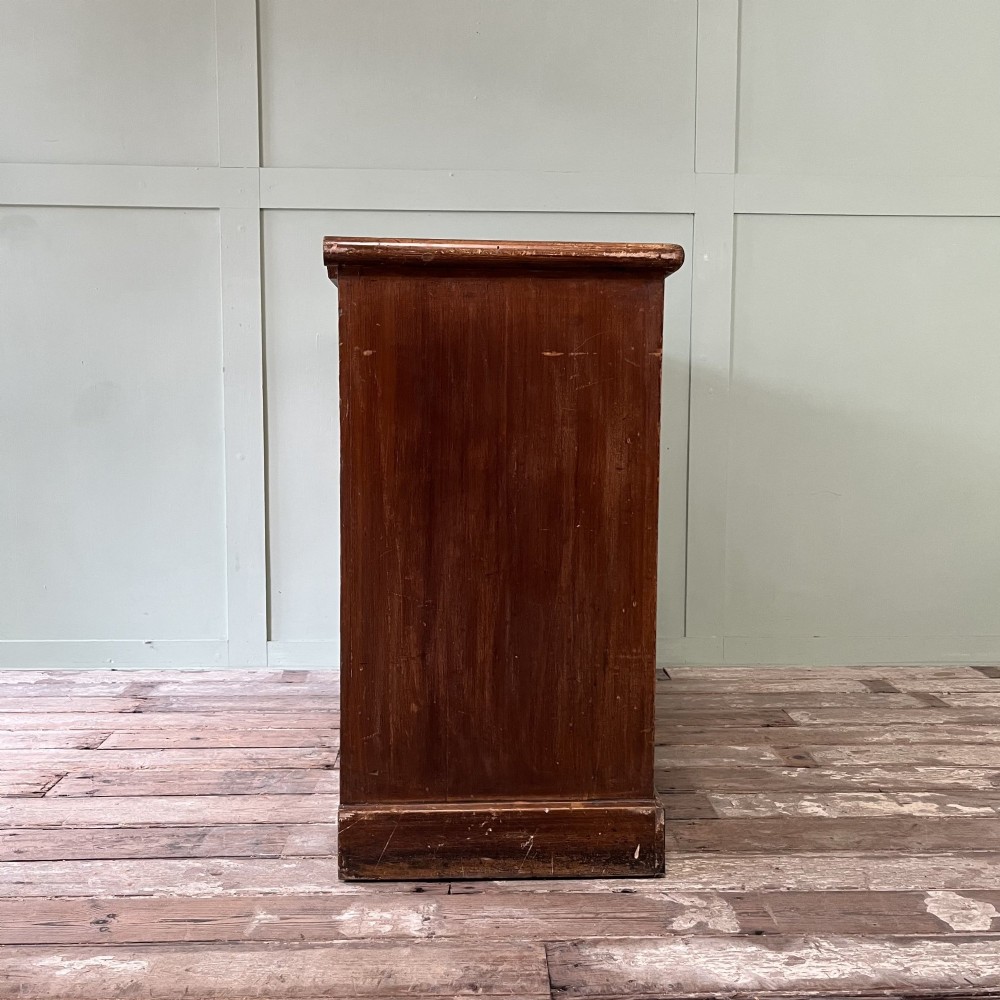 An antique Victorian warm brown pine cupboard featuring three drawers on the left with turned wooden knobs alongside a single panelled door on the right. View XI
