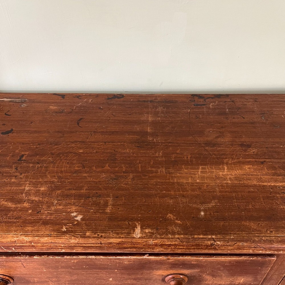 An antique Victorian warm brown pine cupboard featuring three drawers on the left with turned wooden knobs alongside a single panelled door on the right. View XIV