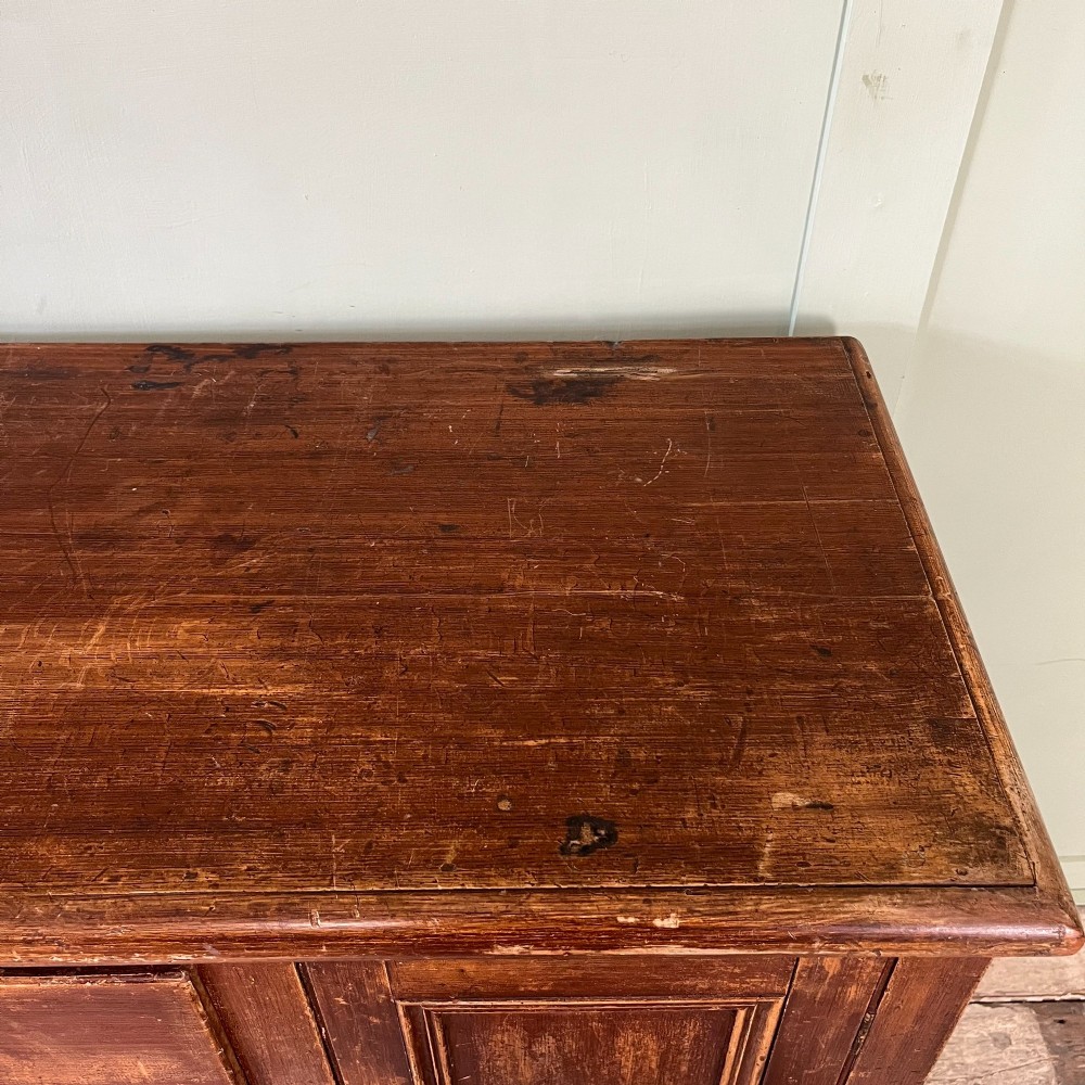 An antique Victorian warm brown pine cupboard featuring three drawers on the left with turned wooden knobs alongside a single panelled door on the right. View XV