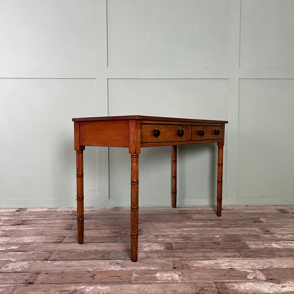 An antique pine hall table featuring two drawers with dark turned handles and slender turned legs. View III