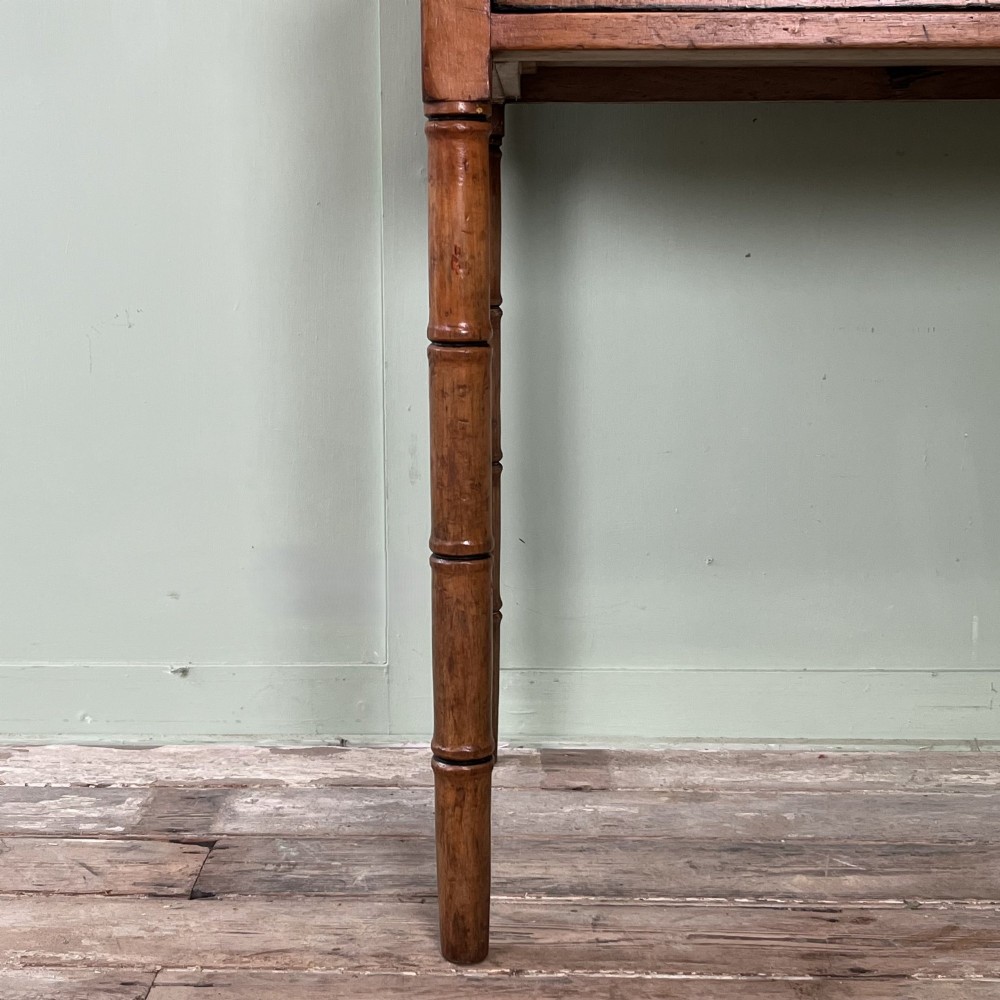 An antique pine hall table featuring two drawers with dark turned handles and slender turned legs. View IV