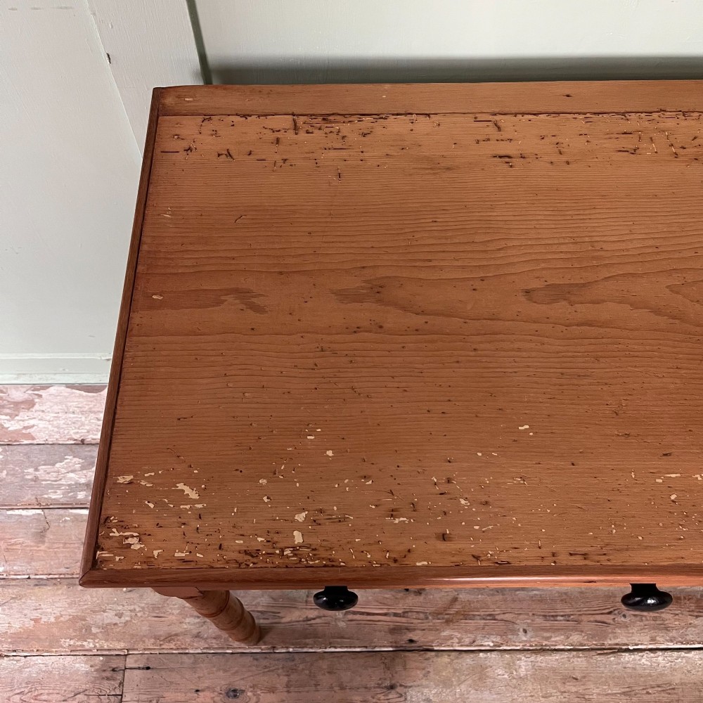 An antique pine hall table featuring two drawers with dark turned handles and slender turned legs. View X