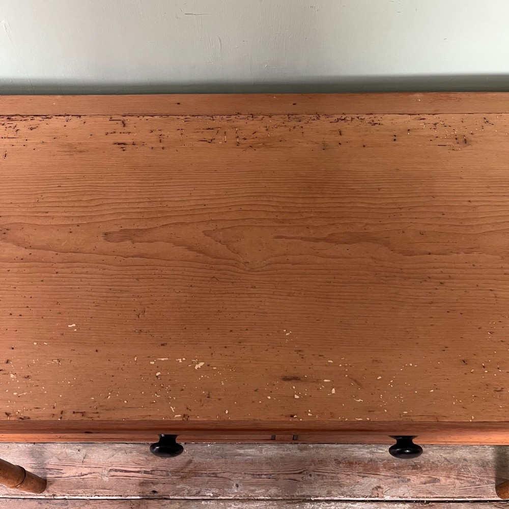 An antique pine hall table featuring two drawers with dark turned handles and slender turned legs. View XII