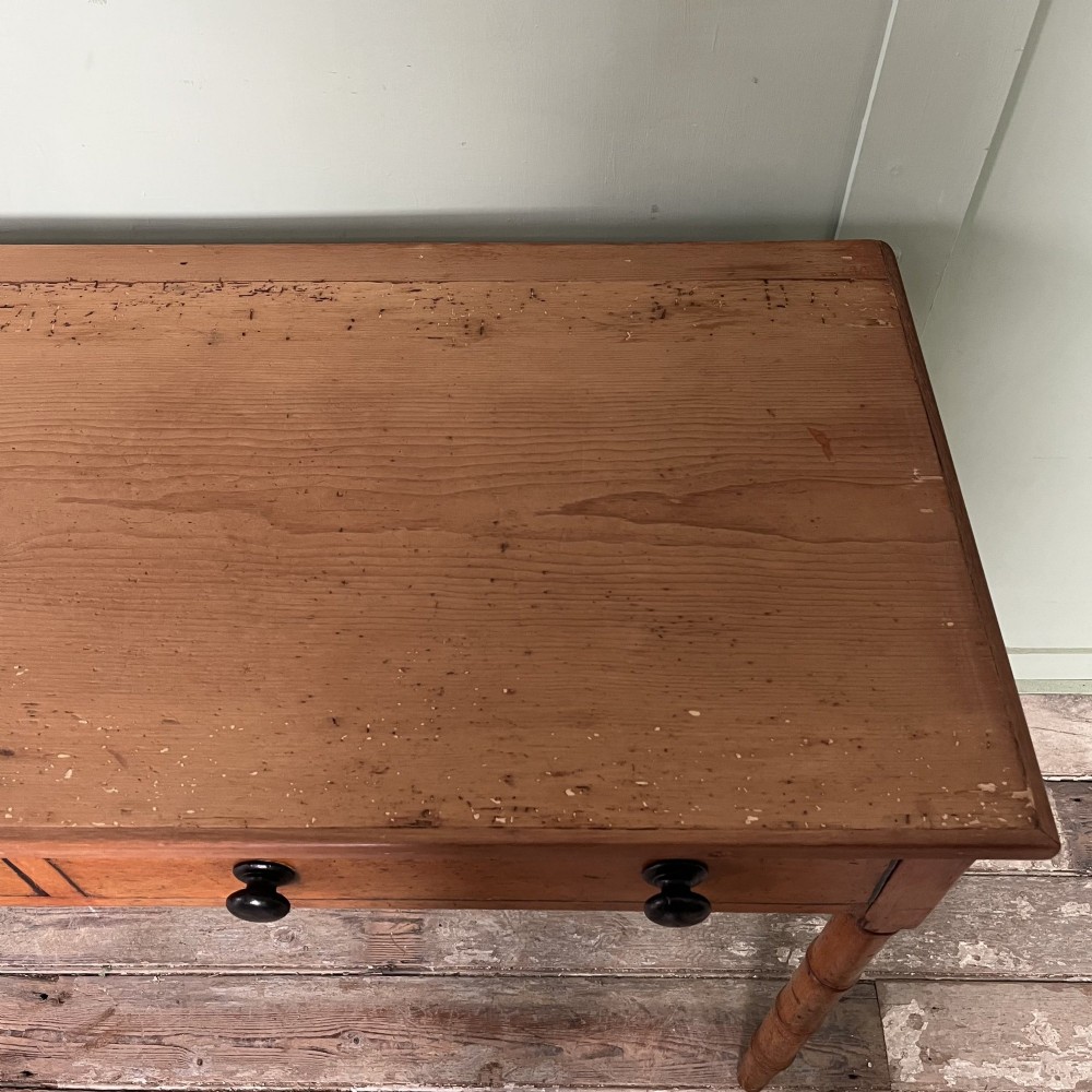 An antique pine hall table featuring two drawers with dark turned handles and slender turned legs. View XIII