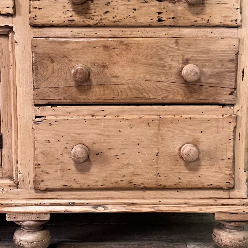 A long Georgian pine sideboard featuring six side drawers flanking a central top drawer and small double-door cupboard, supported by turned bun feet. View VIII