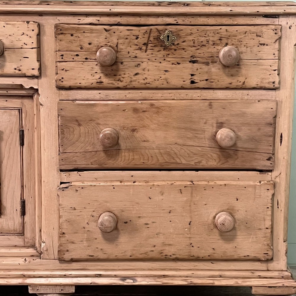 A long Georgian pine sideboard featuring six side drawers flanking a central top drawer and small double-door cupboard, supported by turned bun feet. View IX