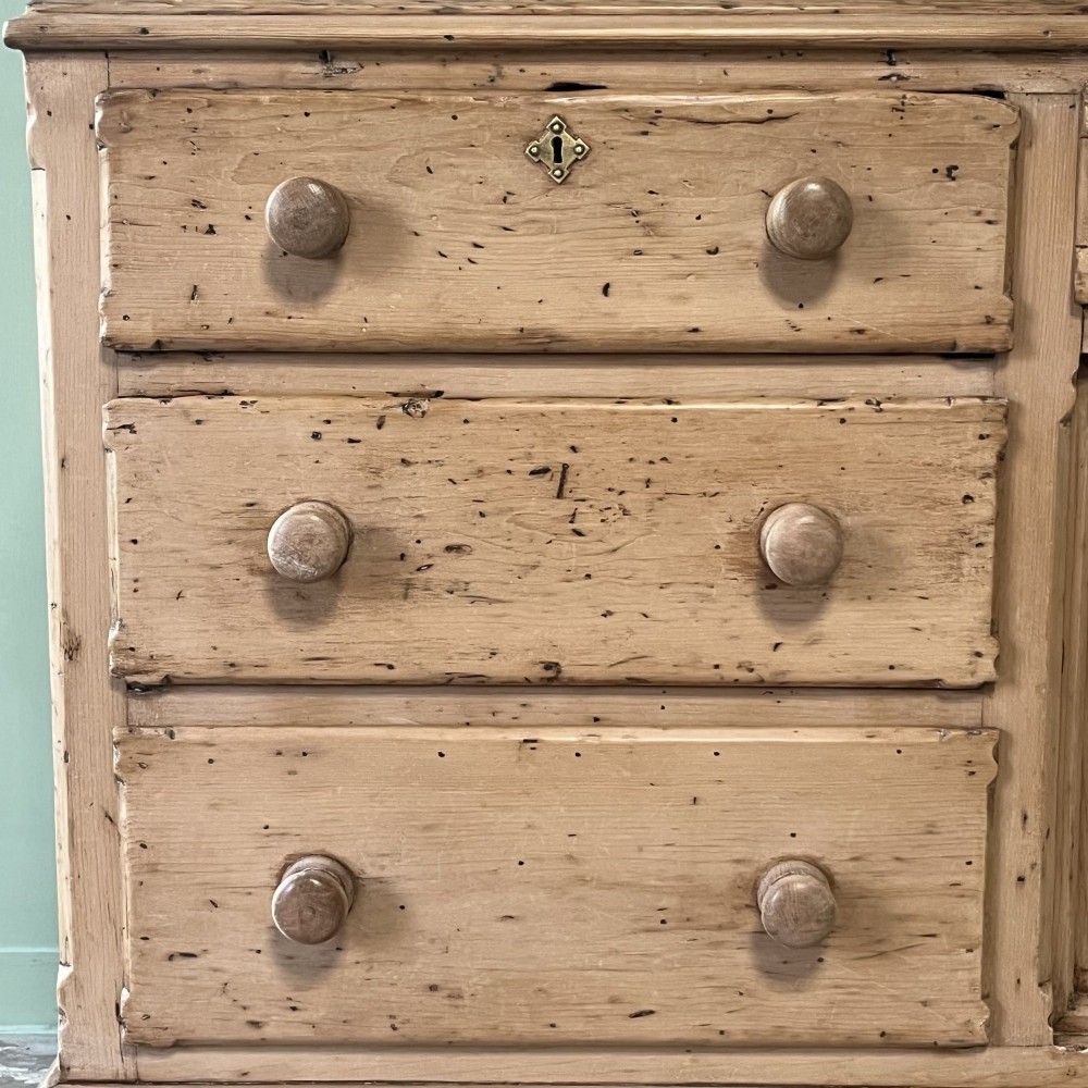 A long Georgian pine sideboard featuring six side drawers flanking a central top drawer and small double-door cupboard, supported by turned bun feet. View X