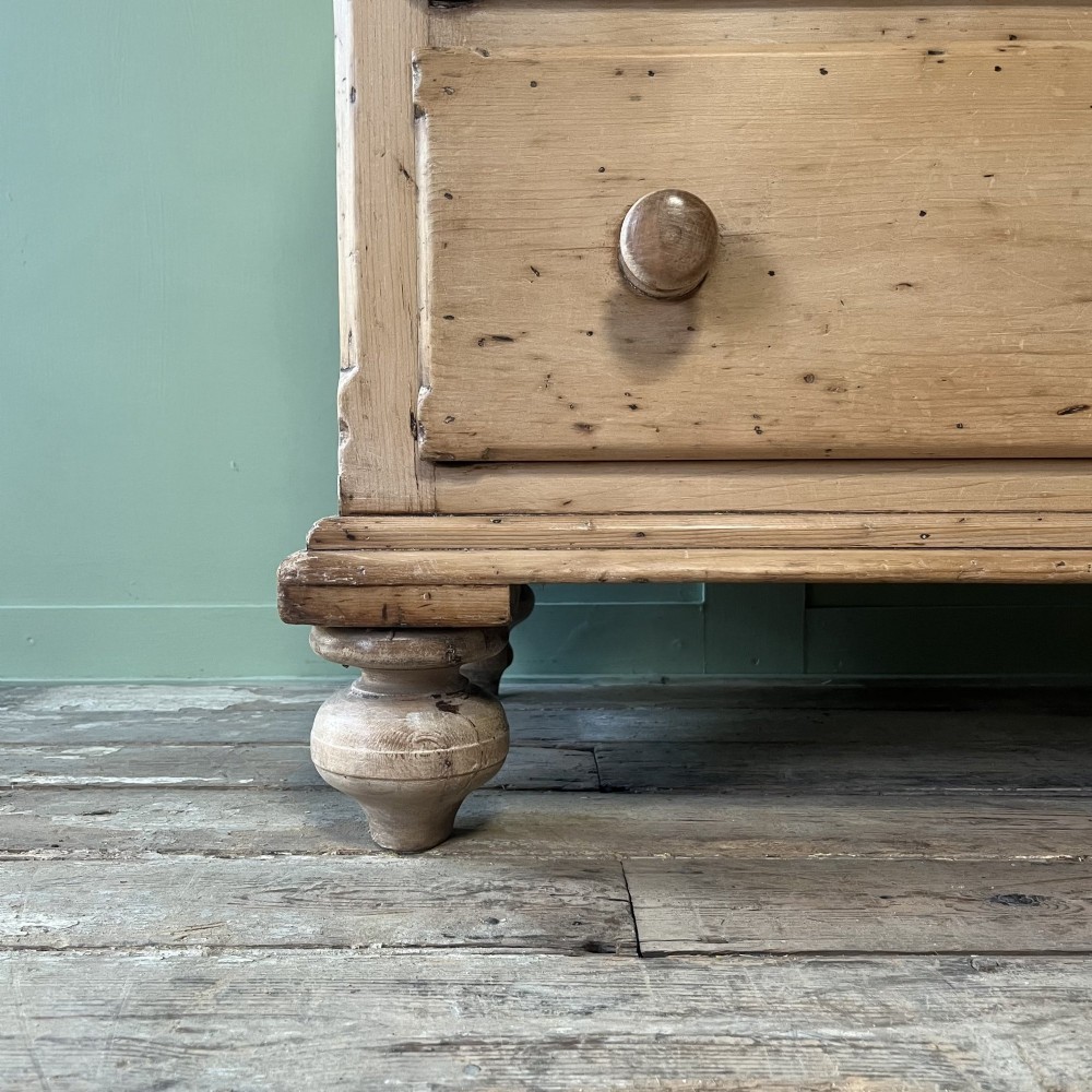 A long Georgian pine sideboard featuring six side drawers flanking a central top drawer and small double-door cupboard, supported by turned bun feet. View XI