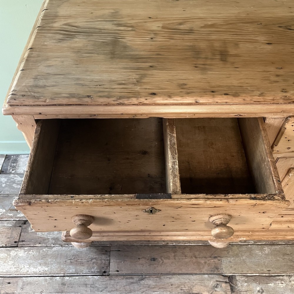 A long Georgian pine sideboard featuring six side drawers flanking a central top drawer and small double-door cupboard, supported by turned bun feet. View XIII