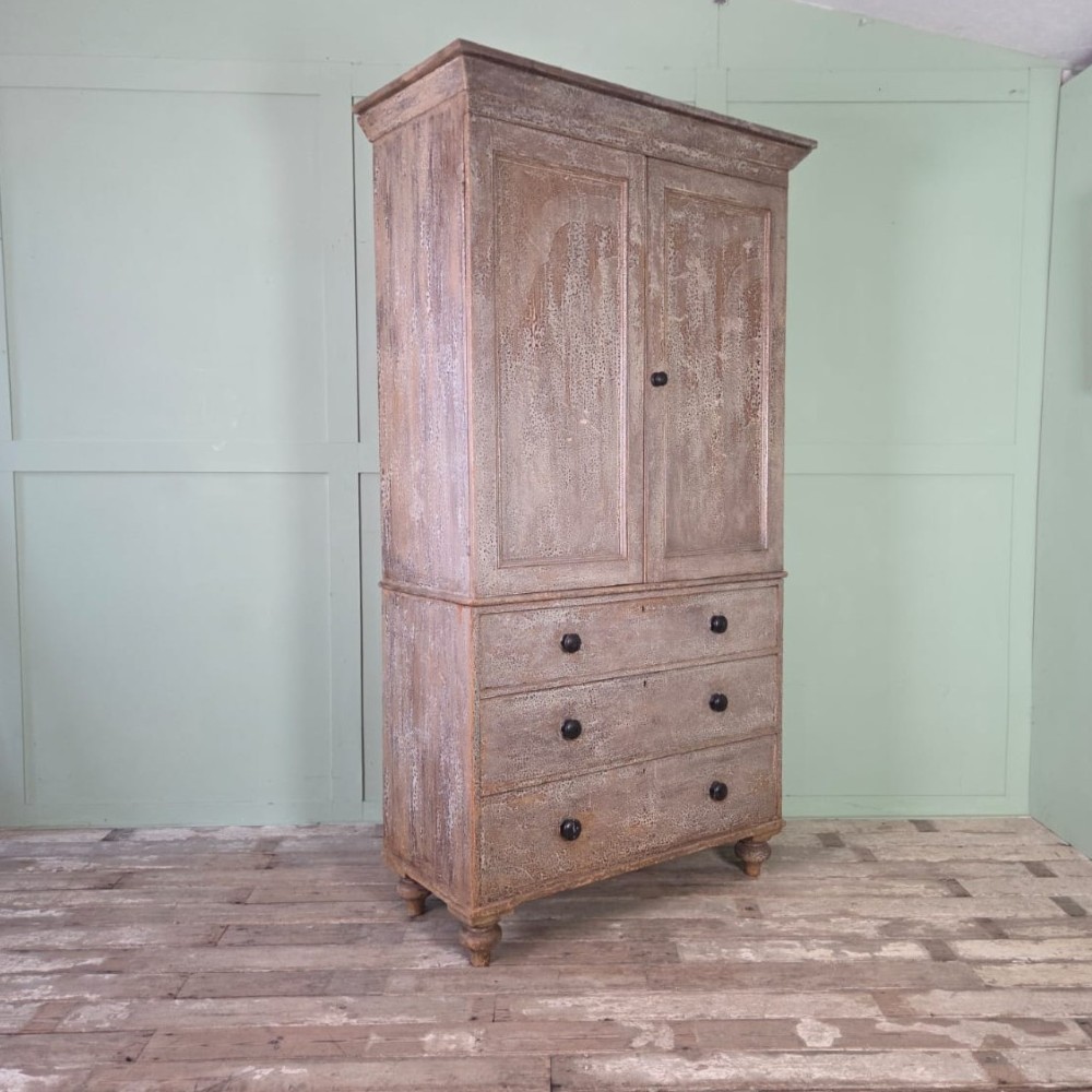 A tall late Georgian painted pine housekeepers cupboard featuring panelled upper doors and three lower drawers on turned feet. View II