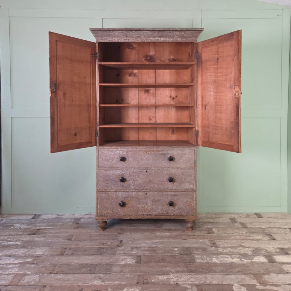 A tall late Georgian painted pine housekeepers cupboard featuring panelled upper doors and three lower drawers on turned feet. View IV