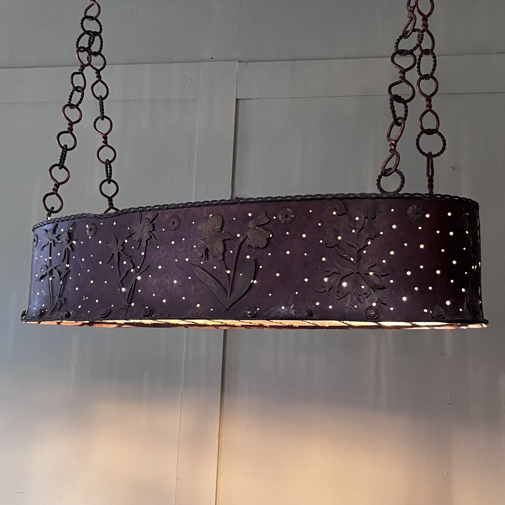 An oval Arts and Crafts copper pendant light featuring hand-chased floral motifs suspended from twin copper link chains with ceiling roses. View IV