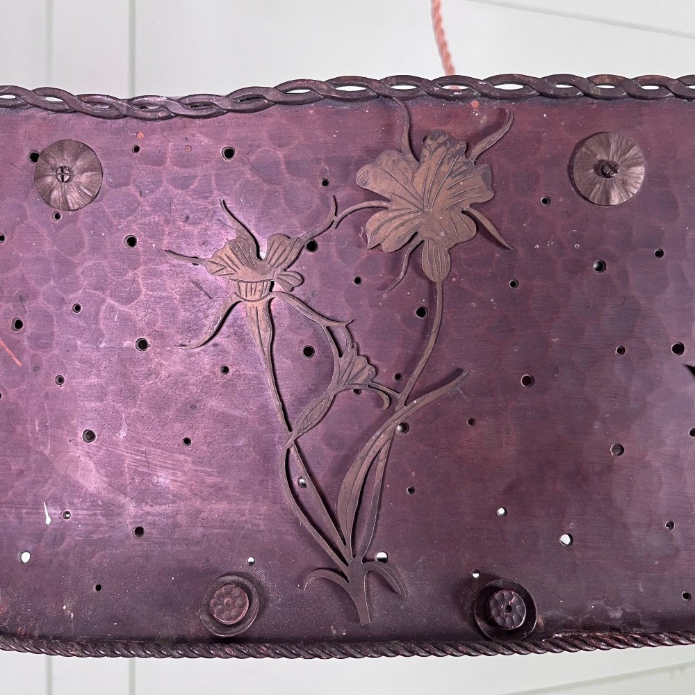 An oval Arts and Crafts copper pendant light featuring hand-chased floral motifs suspended from twin copper link chains with ceiling roses. View VII
