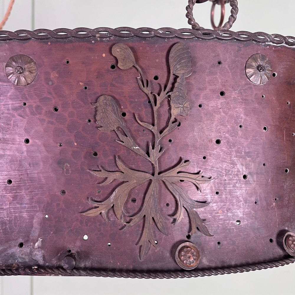 An oval Arts and Crafts copper pendant light featuring hand-chased floral motifs suspended from twin copper link chains with ceiling roses. View IX