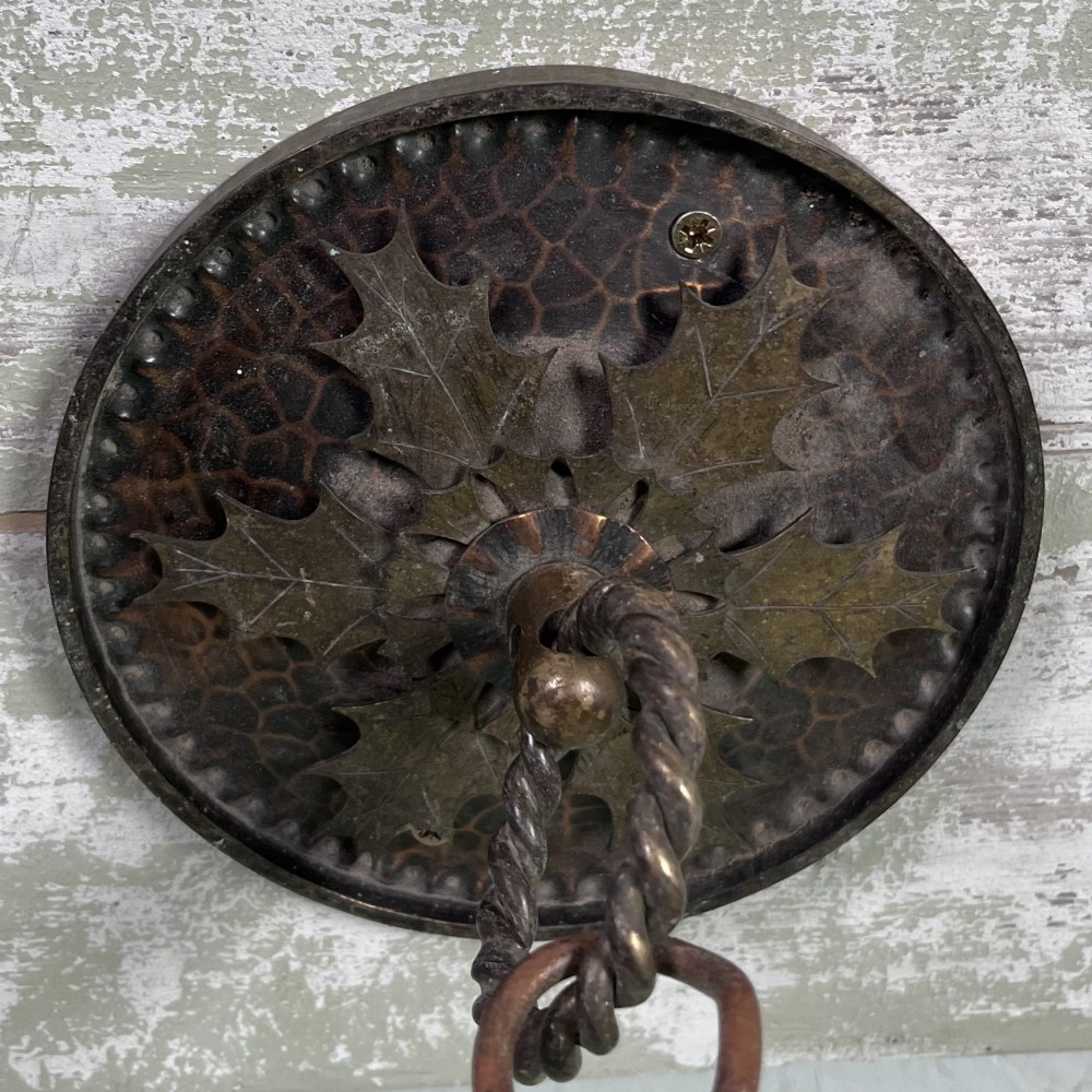 An oval Arts and Crafts copper pendant light featuring hand-chased floral motifs suspended from twin copper link chains with ceiling roses. View XII