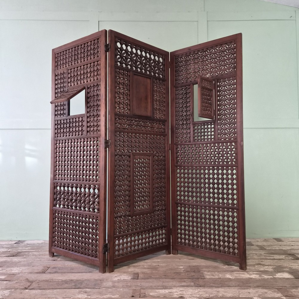 A three-panel antique wooden folding screen featuring intricate turned spindle lattice work and geometric carved panels in a dark brown finish. View II