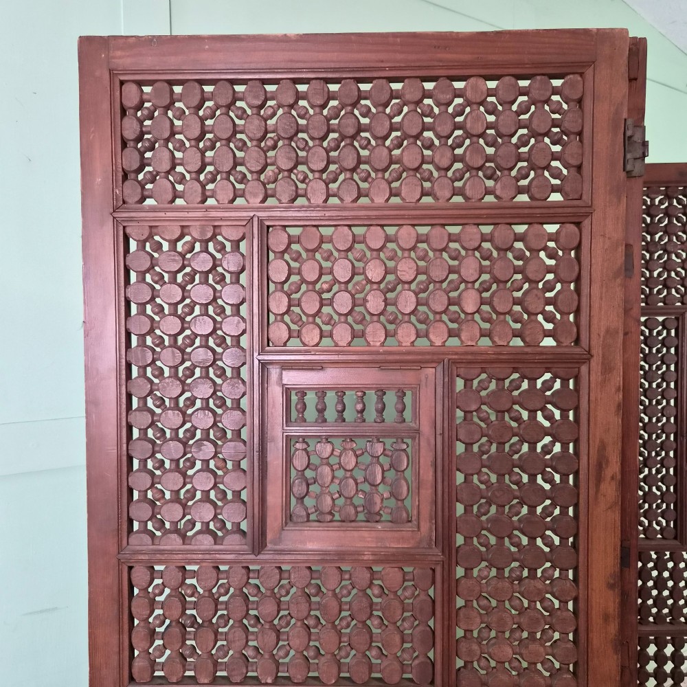 A three-panel antique wooden folding screen featuring intricate turned spindle lattice work and geometric carved panels in a dark brown finish. View III