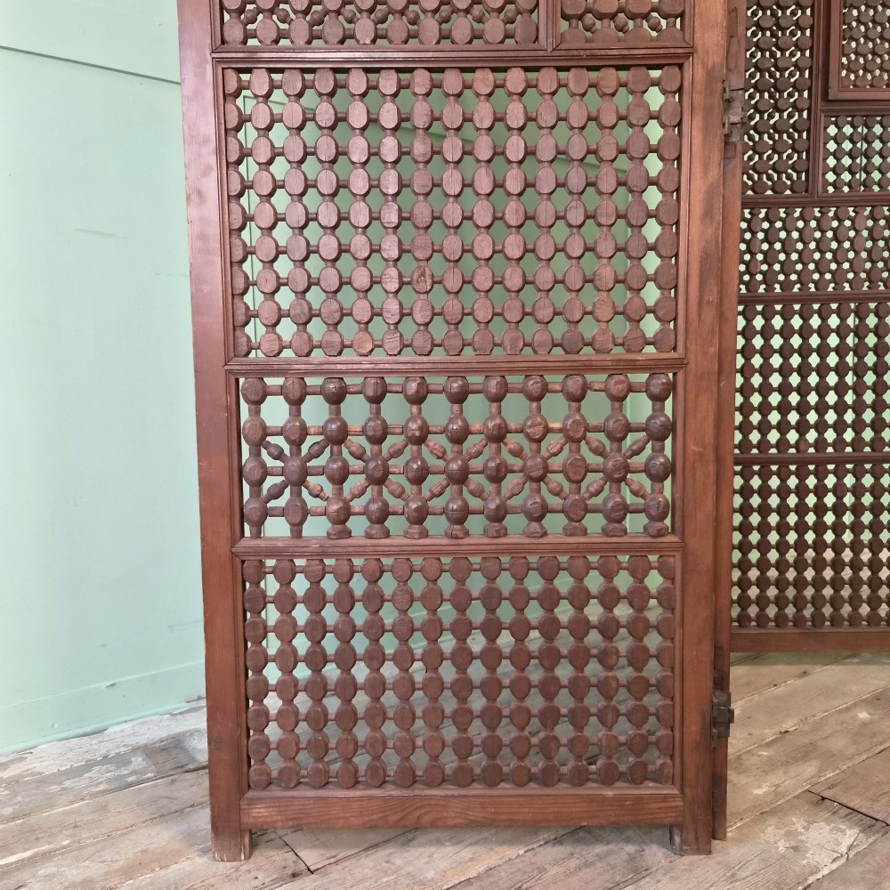 A three-panel antique wooden folding screen featuring intricate turned spindle lattice work and geometric carved panels in a dark brown finish. View IV