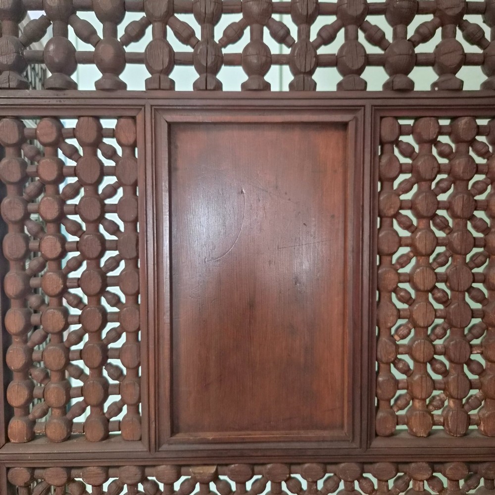 A three-panel antique wooden folding screen featuring intricate turned spindle lattice work and geometric carved panels in a dark brown finish. View VII