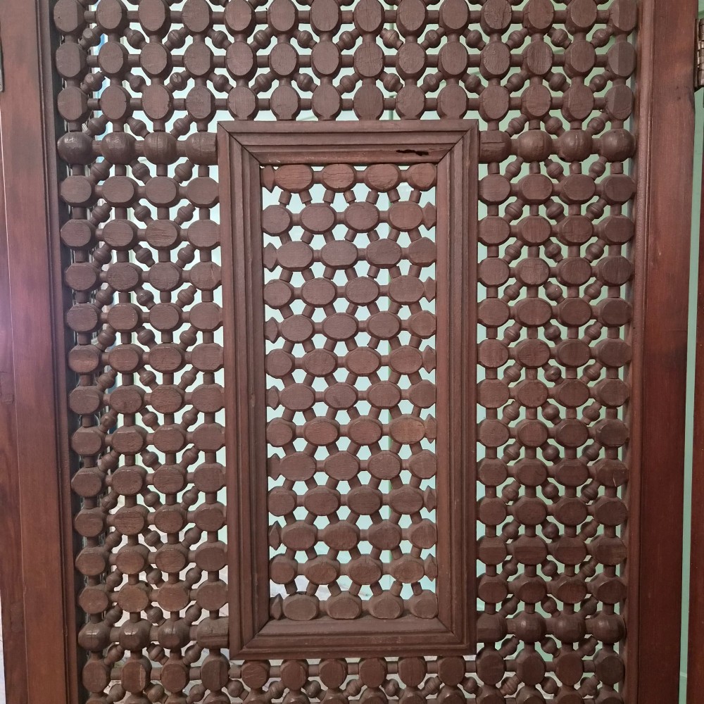 A three-panel antique wooden folding screen featuring intricate turned spindle lattice work and geometric carved panels in a dark brown finish. View VIII