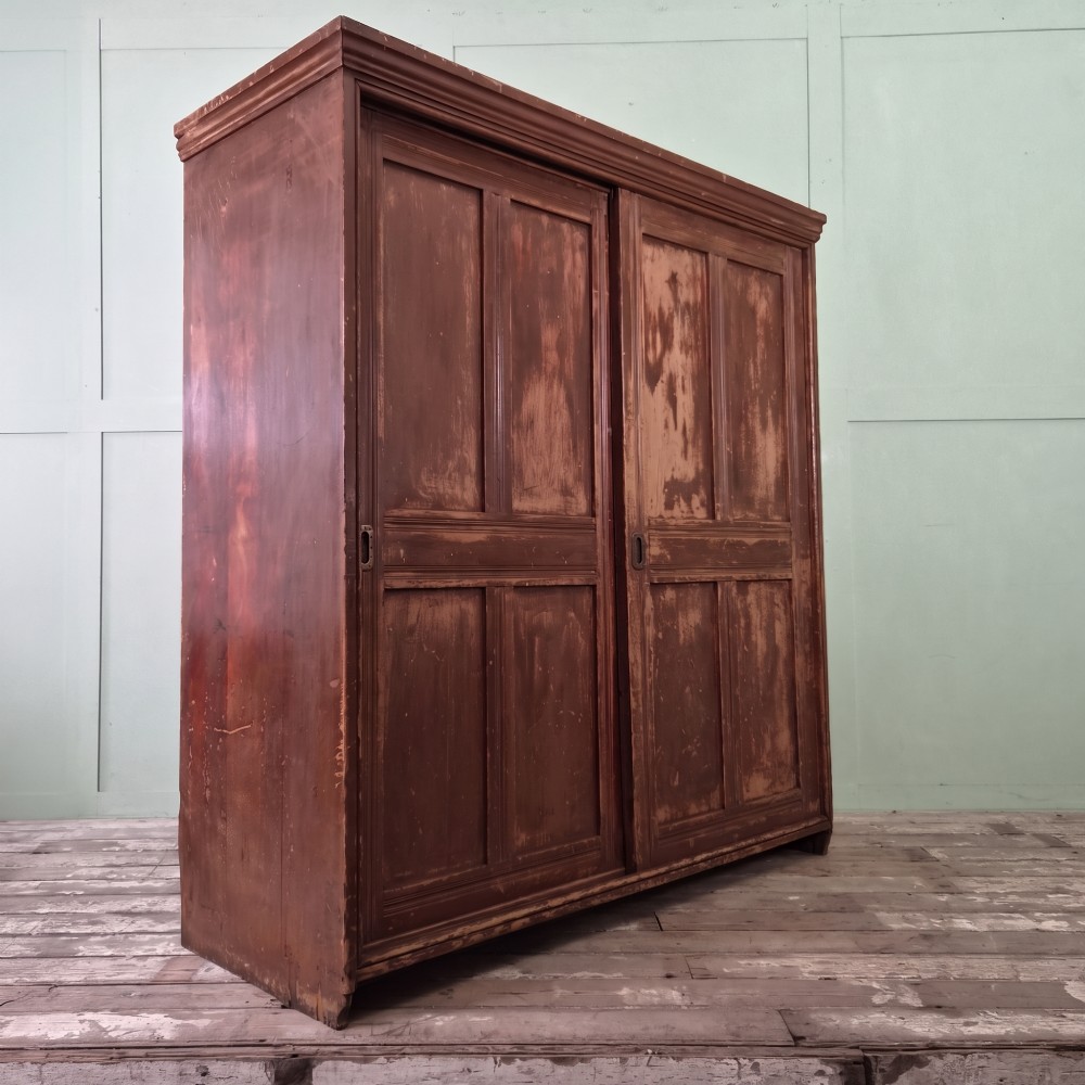A large 19th-century pine freestanding cupboard featuring two sliding panel doors with an aged reddish-brown patinated finish and a moulded top cornice. View III