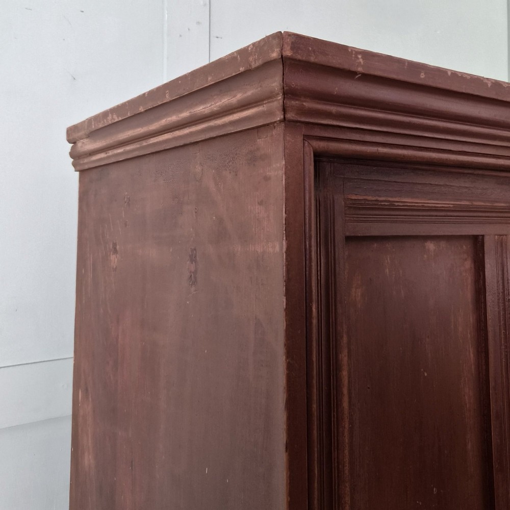 A large 19th-century pine freestanding cupboard featuring two sliding panel doors with an aged reddish-brown patinated finish and a moulded top cornice. View IV