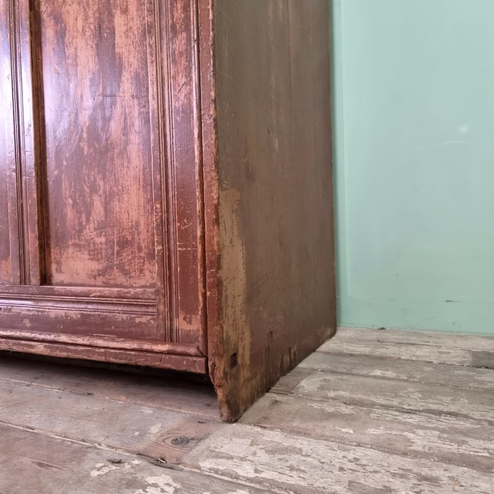 A large 19th-century pine freestanding cupboard featuring two sliding panel doors with an aged reddish-brown patinated finish and a moulded top cornice. View VIII