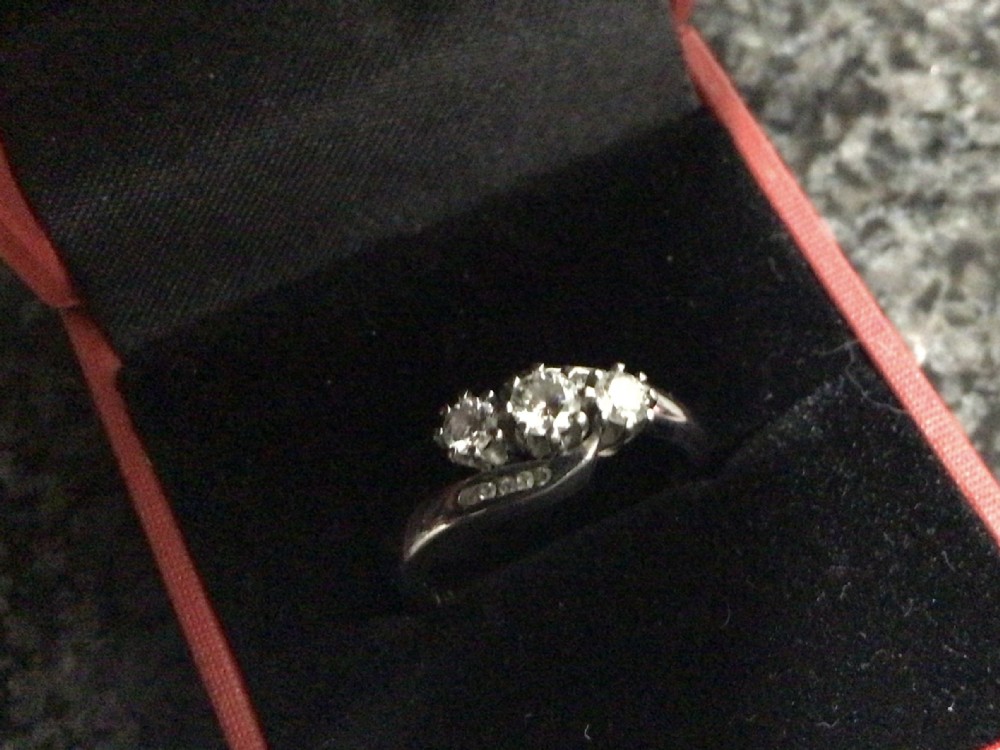 A platinum diamond crossover ring featuring three claw-set round diamonds set on a twisted platinum band.