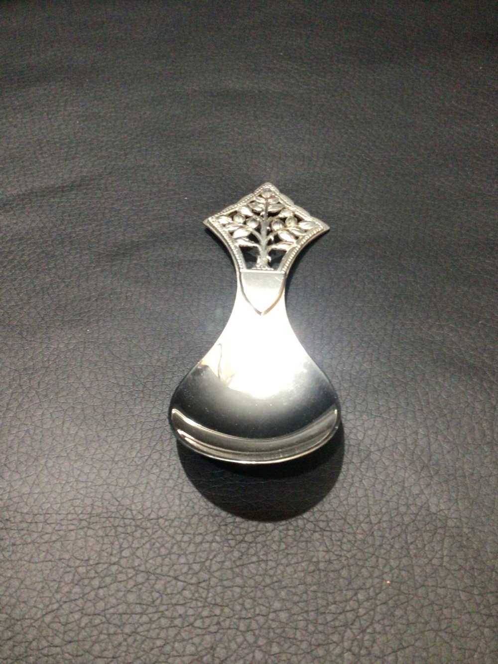 A sterling silver tea caddy spoon featuring a pierced diamond-shaped handle decorated with a tree of life motif and a polished pear-shaped bowl. View VIII