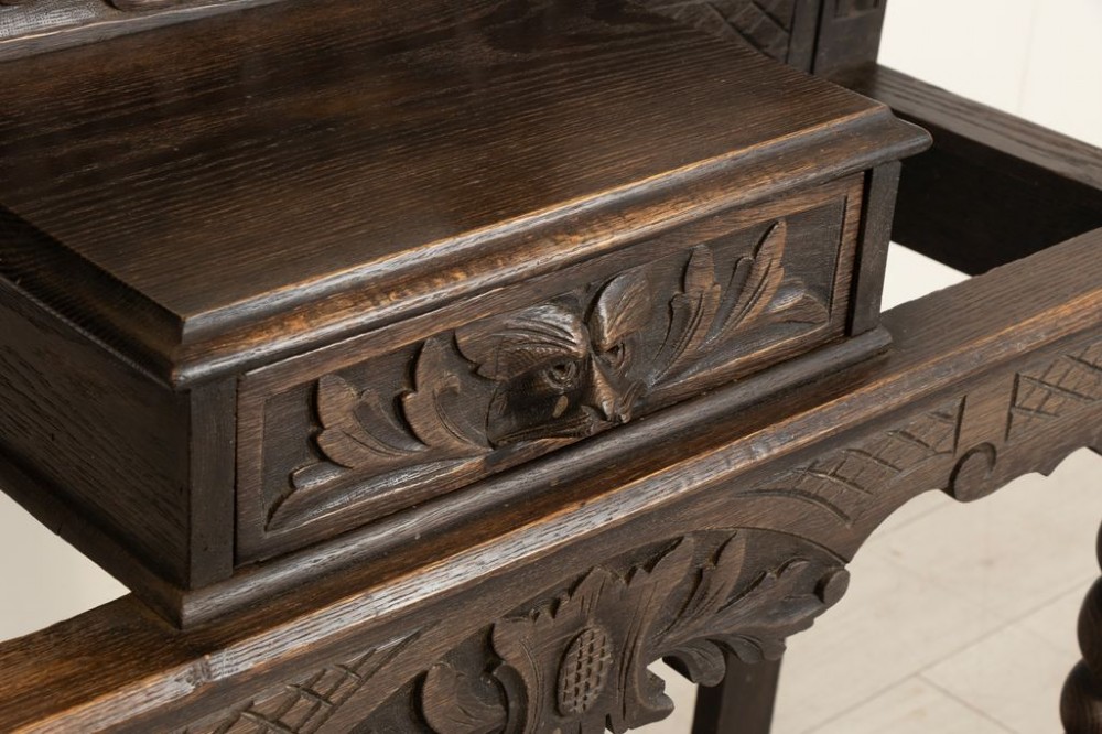 A late Victorian carved dark oak hall stand featuring a central mirror, dragon motifs, barley twist supports, integrated coat hooks, and an umbrella stand base. View IV