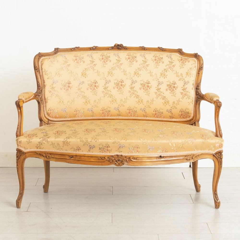 A three-piece antique French salon suite comprising a small canape sofa and two matching armchairs with carved pale walnut frames and gold floral upholstery. View II
