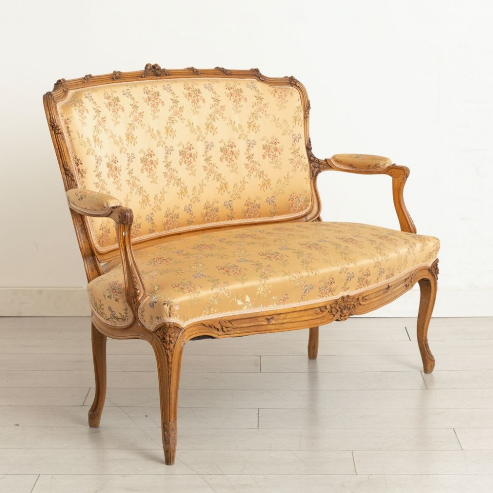 A three-piece antique French salon suite comprising a small canape sofa and two matching armchairs with carved pale walnut frames and gold floral upholstery. View III