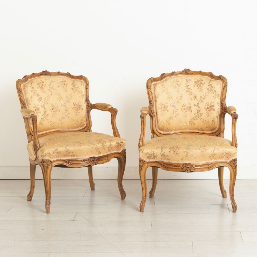 A three-piece antique French salon suite comprising a small canape sofa and two matching armchairs with carved pale walnut frames and gold floral upholstery. View IV