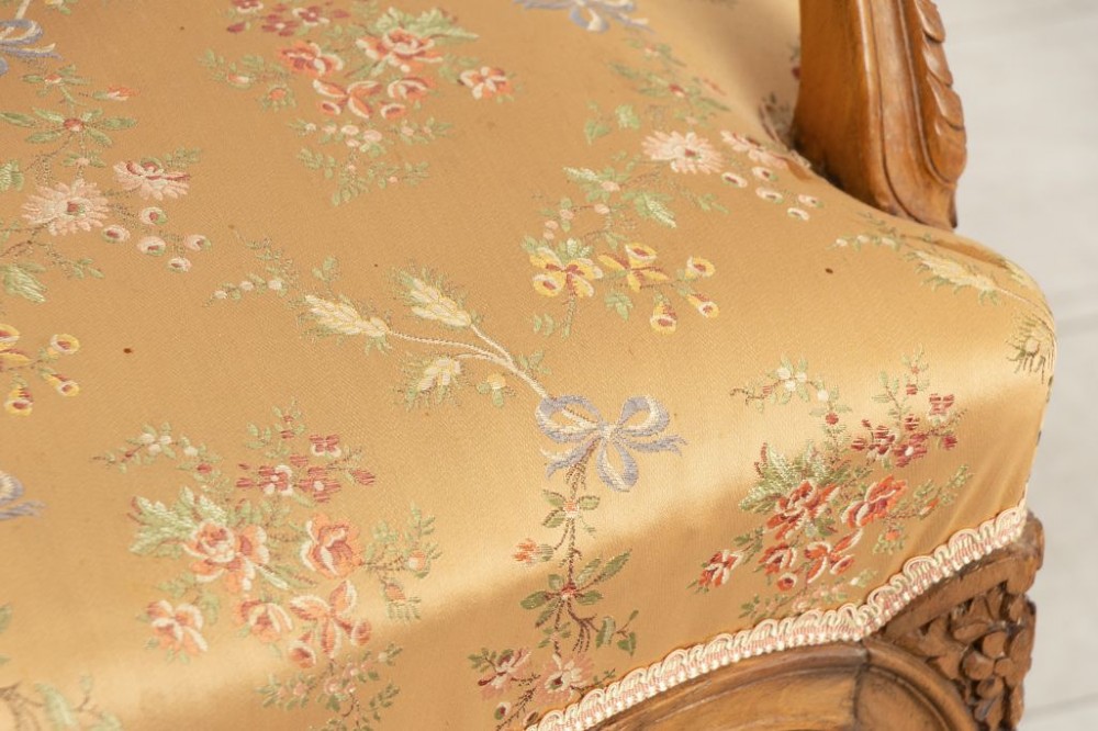 A three-piece antique French salon suite comprising a small canape sofa and two matching armchairs with carved pale walnut frames and gold floral upholstery. View VI