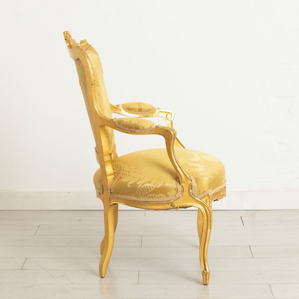 A pair of carved French Rococo giltwood armchairs upholstered in yellow silk floral damask fabric. View II