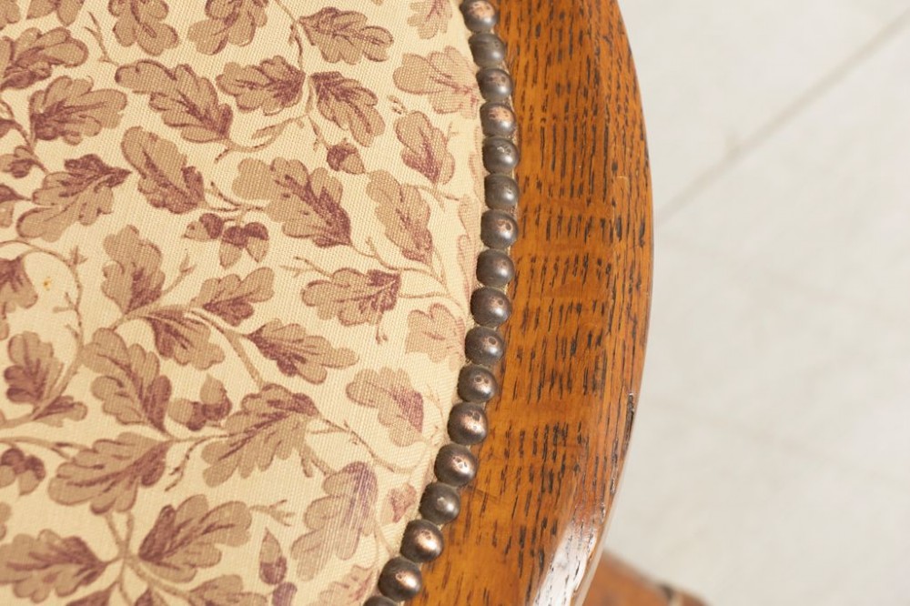 A Victorian Gothic Revival oak swivel desk chair featuring a curved crest rail, pierced quatrefoil splat back, upholstered seat, and splayed legs on brass castors. View III