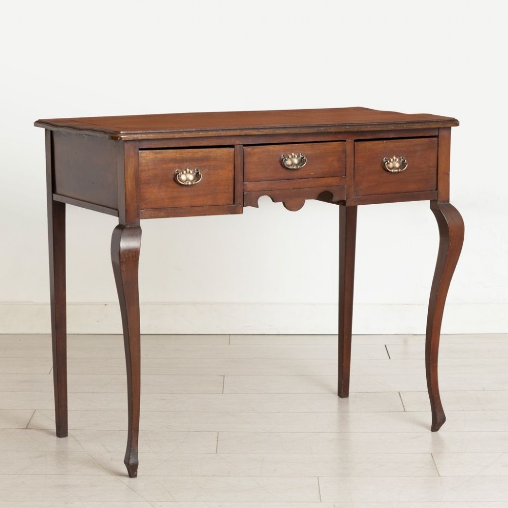 An Edwardian mahogany ladies writing desk featuring a brown leather inlaid top, three frieze drawers with brass handles, and slender cabriole legs. View II