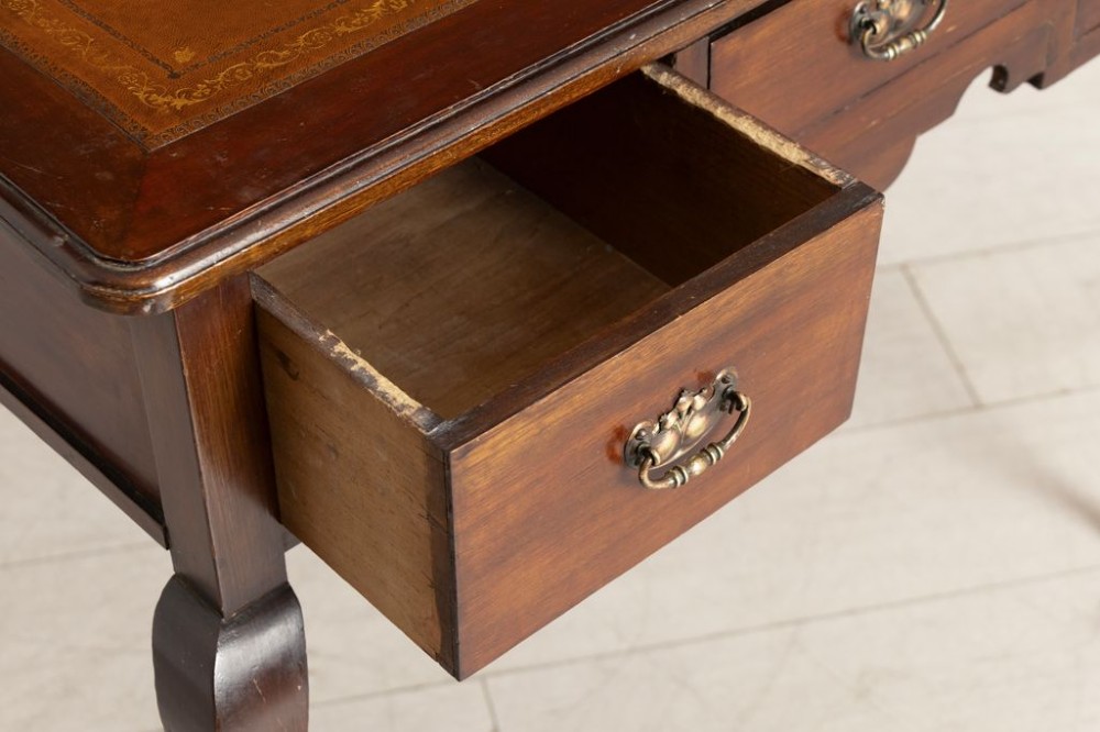 An Edwardian mahogany ladies writing desk featuring a brown leather inlaid top, three frieze drawers with brass handles, and slender cabriole legs. View III